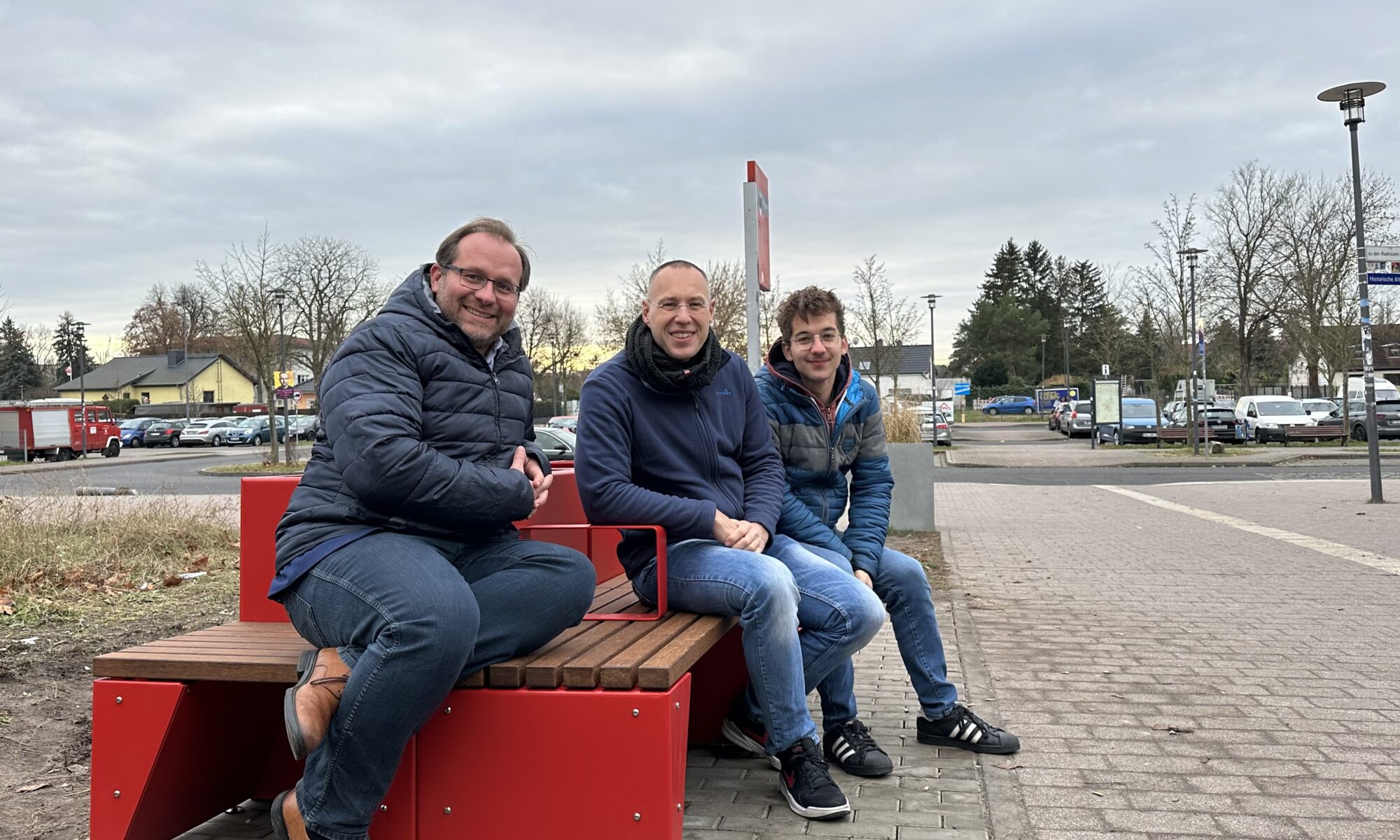 Nauens Bürgermeister Herr Meger und Kollegen aus dem i2030-Team sitzen auf der neuen i2030-Bank vor dem Bahnhof Nauen Bild: Stadt Nauen